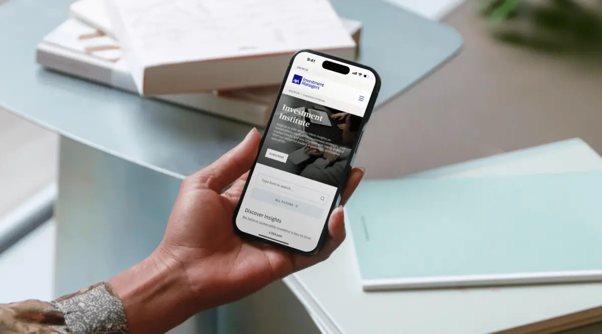 Hand holding a phone showing the AXA IM Investment Institute page