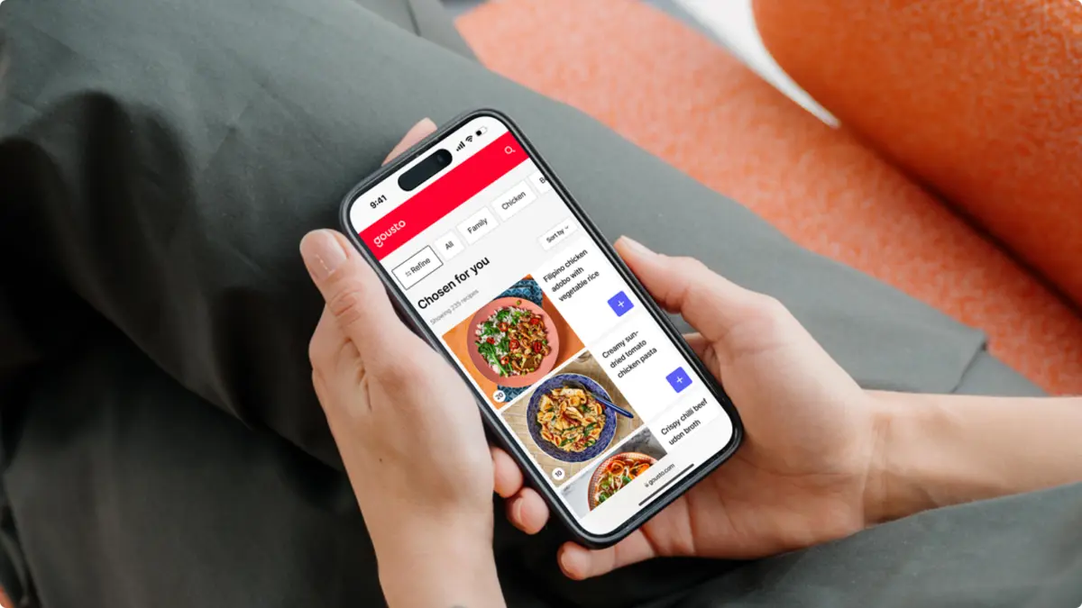 Hands holding a phone showing Gousto's 'Chosen for you' recipe menu